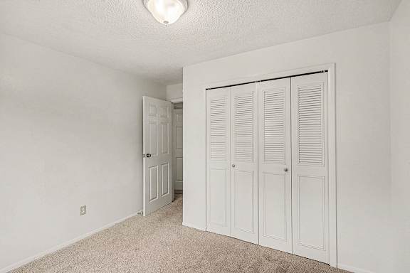 A bedroom with a large closet and carpeted floor at Waverly Park Apartments, Lansing, Michigan