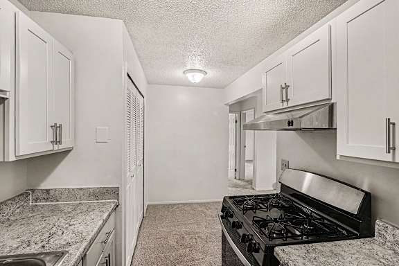 A kitchen with a stainless steel stove top oven and white shaker cabinets at Waverly Park Apartments, Lansing, Michigan