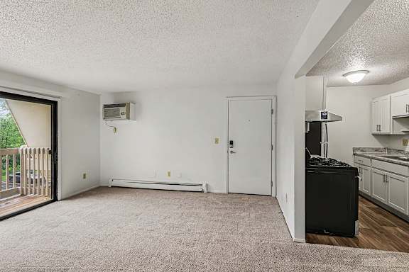 A living room with sliding glass doors to a balcony at Waverly Park Apartments, Lansing, Michigan