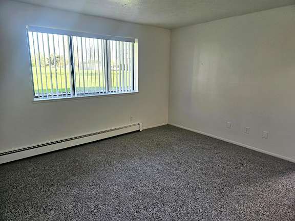 A living room with a garden window and carpeted floor A living room with a garden window and carpeted floor at Waverly Park Apartments, Lansing