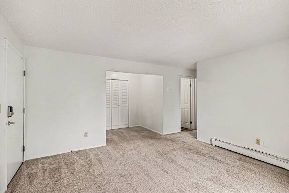 A living and dining room with a carpeted floor at Waverly Park Apartments, Lansing, Michigan