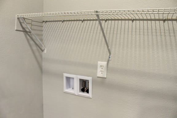 a wire closet organizer hangs on the wall next to two outlets
