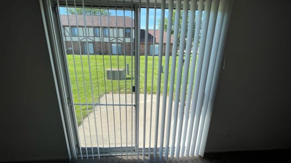 a sliding glass door with a view of a yard and a building