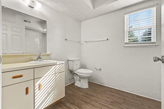 A white bathroom with a toilet, sink, mirror and window at West Hampton Park Apartment Homes, Nebraska, 68022