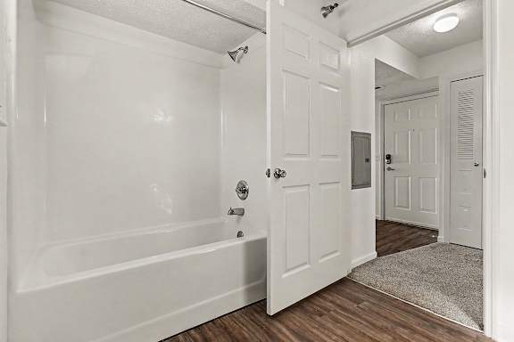 A white bathroom with a bathtub and shower at West Hampton Park Apartment Homes, Nebraska, 68022