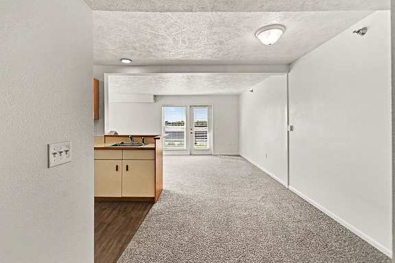 A kitchen area with a breakfast bar and a spacious dining and living room leading to a patio at West Hampton Park Apartment Homes, Nebraska, 68022