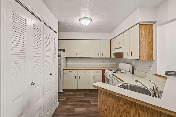 A kitchen with wooden cabinets and white appliances at West Hampton Park Apartment Homes, Nebraska, 68022