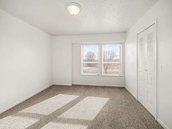 A bedroom with a carpeted floor and a window  at West Hampton Park Apartment Homes, Nebraska, 68022