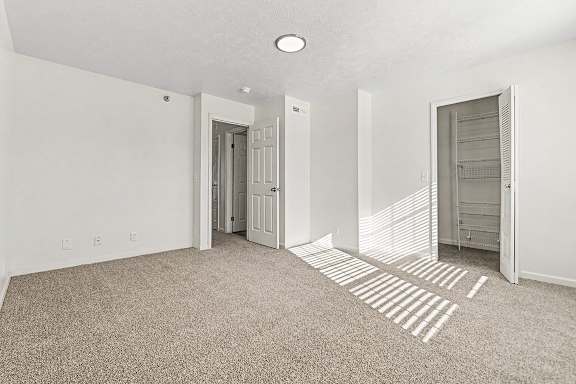 A bedroom with a carpeted floor and a walk-in closet  at West Hampton Park Apartment Homes, Nebraska, 68022