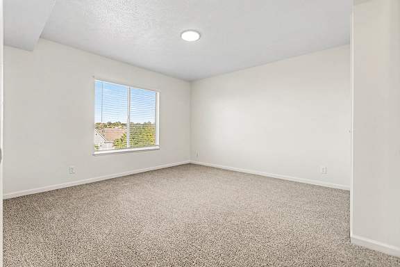 A bedroom with a carpeted floor and a large window  at West Hampton Park Apartment Homes, Nebraska, 68022