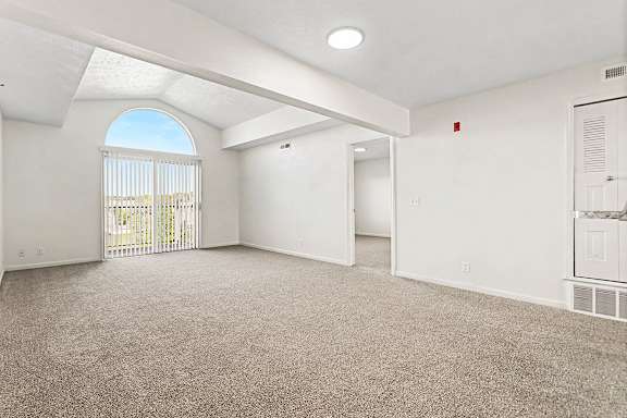 A spacious living room with a large window and a door leading to a balcony  at West Hampton Park Apartment Homes, Nebraska, 68022