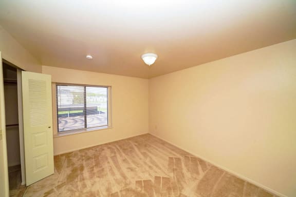 bedroom with a large window and a walk-in closet at Windmill Lakes Apartments, Holland, 49424