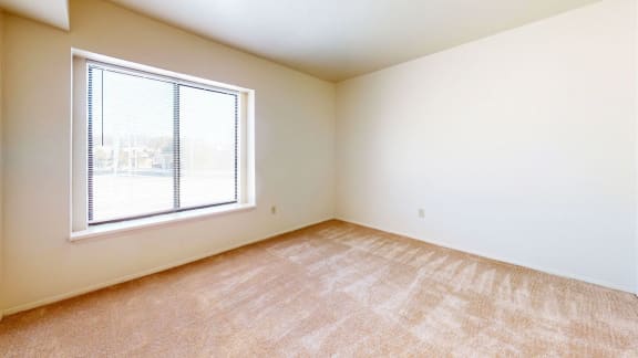 bedroom with a large window and carpeting at Windmill Lakes Apartments, Holland, 49424
