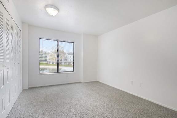 A room with a window and a carpeted floor.
