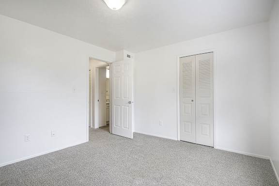 A white room with a carpeted floor and two doors.