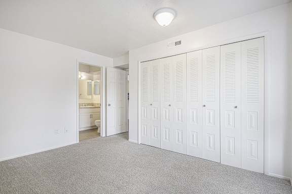 A white room with a row of white closet doors.