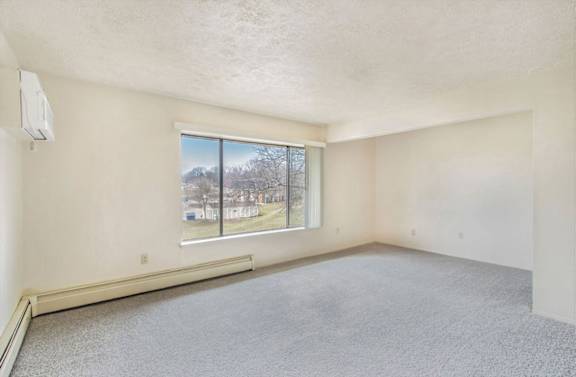 A living room with a window and plush carpet at Wingate Apartments, Kentwood, 49512