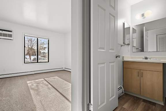 An ensuite bathroom with maple cabinetry, a mirror, and a sink at Wood Creek Apartments, Kenosha