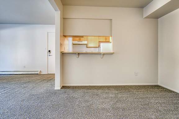 A dining room with a carpeted floor and a breakfast bar at Wood Creek Apartments, Kenosha