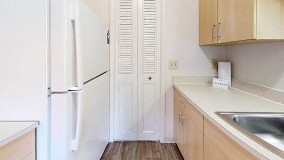 A kitchen with a white fridge and wooden cabinets at Wood Creek Apartments in Kenosha, WI