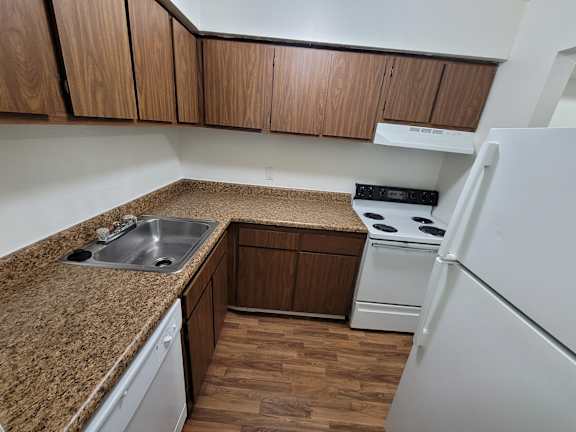 A kitchen with a brown countertop and white appliances.