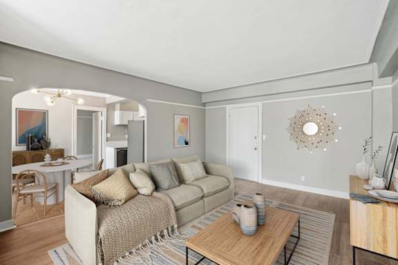 A living room with a couch, coffee table, and a dining table.