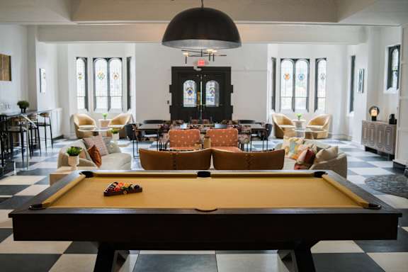 A pool table is in the middle of a room with a black and white checkered floor.