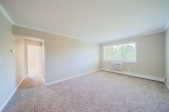 Living room with window and carpeting leading to hallway