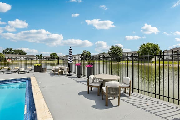 A pool area with a table and chairs and a lighthouse in the background.