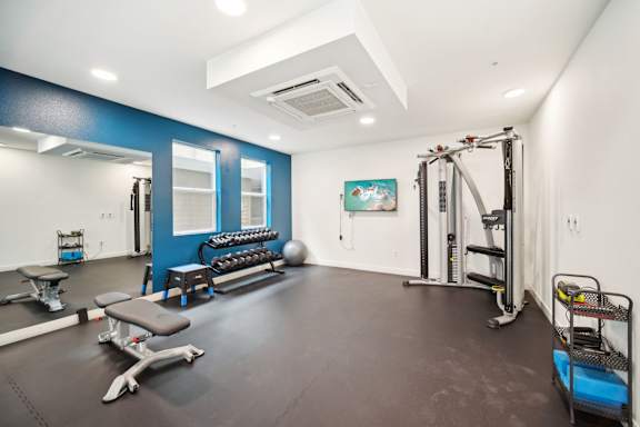 A gym with a variety of equipment including a leg press machine, a bench, and a weight rack.
