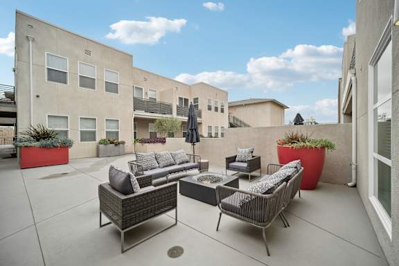 A patio with a couch, chairs, and a table with a black umbrella.