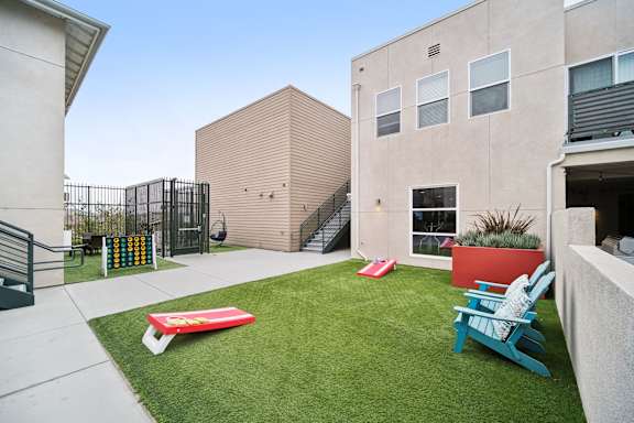 A small backyard with a red and blue chair and a green lawn.