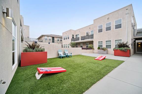 A red bench is in the middle of a green lawn.