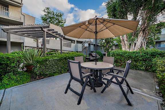 A patio with a table and chairs under an umbrella.
