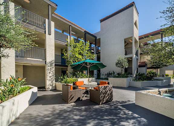 a patio with tables and chairs in front of an apartment building