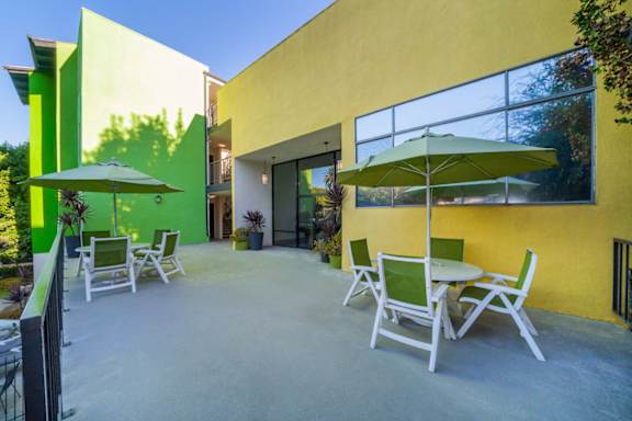 A patio with a table and chairs and a green umbrella.