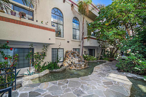 A house with a stone fountain in front of it.