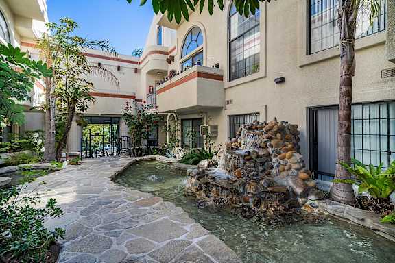 A stone fountain is in the middle of a courtyard.
