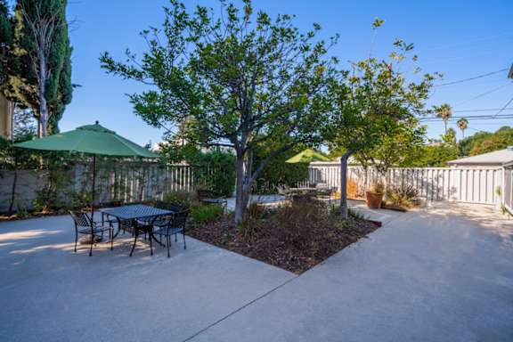 A patio with a table and chairs and a green umbrella.