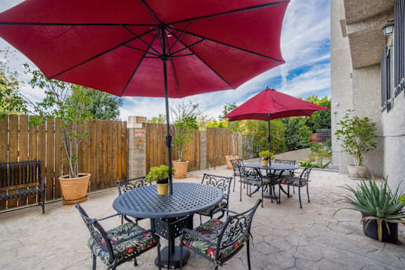 A patio with a table and chairs under a red umbrella.