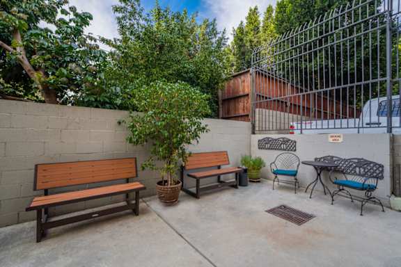 A patio with a table, chairs, and a bench.