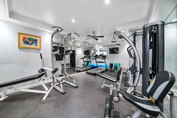 a home gym with exercise equipment and a ceiling fan