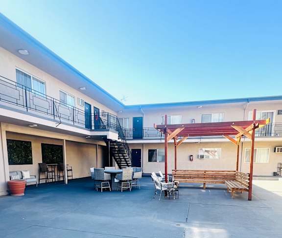 A patio area with a table and chairs is surrounded by two buildings.