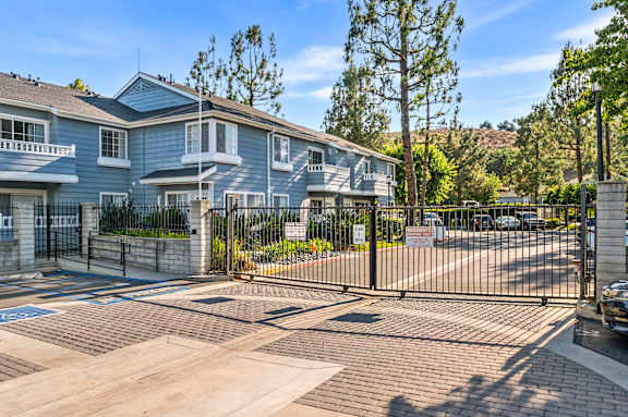 A gated entrance to a residential complex with a blue building.