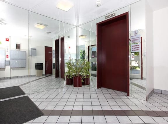 A hallway with a red door and a plant in a red pot.