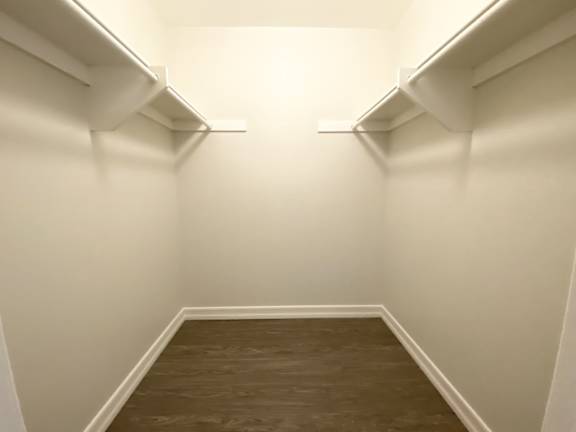 A long, narrow hallway with white walls and wood flooring.