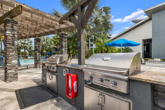 a backyard with two stainless steel barbecue grills and a picnic table