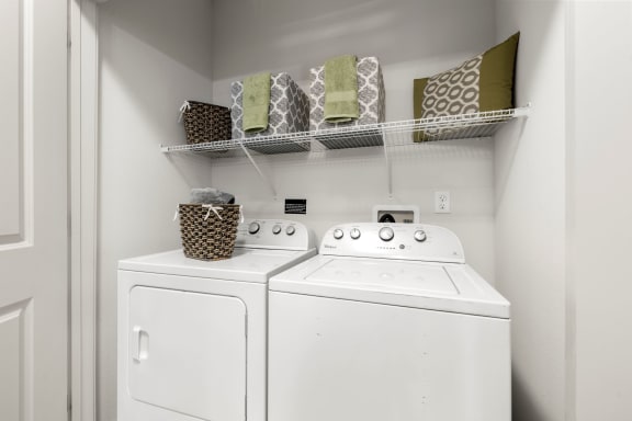 a white washer and dryer in a laundry room with a shelf above it