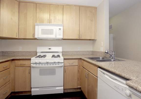 an empty kitchen with a stove microwave and sink