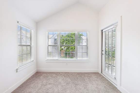 A room with a carpeted floor and a window with blinds.